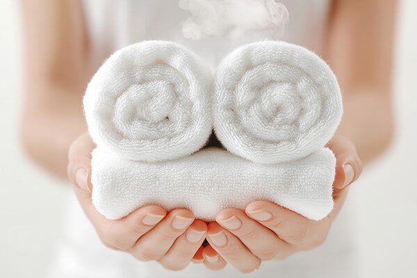 Two white towels held in hands against a neutral background